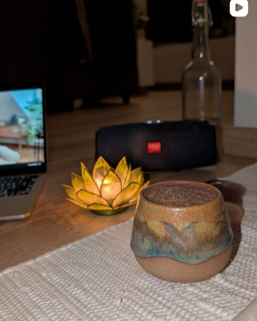 Eine Tasse Kakao neben einer Lotus-Kerze auf einem gewebten Tischläufer